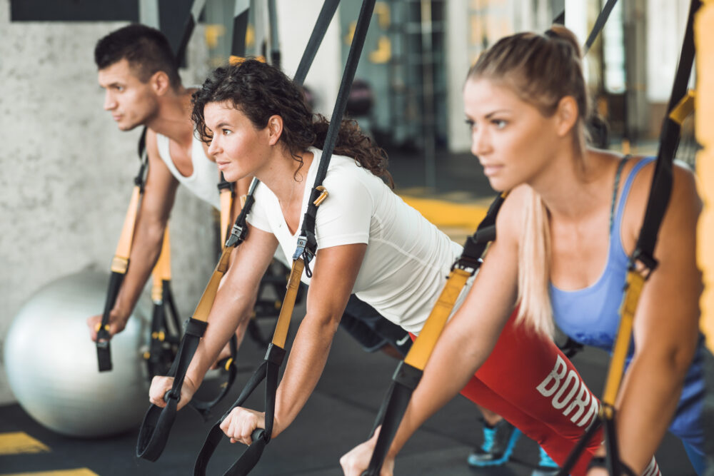 group people doing workout with fitness strap health club